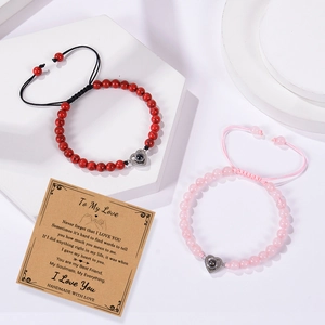 Detail of heart projection couple bracelets with woven beads on white geometric display stand