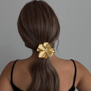 Elegant gold flower hair clip with pearl center and textured metal finish on model