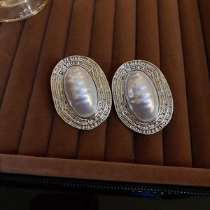 Detailed view of vintage silver earrings with oval faux pearl on brown velvet