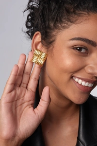 Close-up of model wearing gold square earring with quilted woven texture on ear