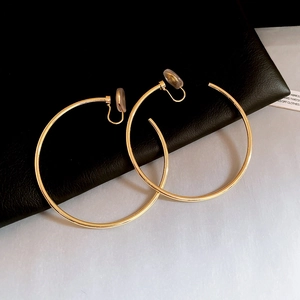 Detail of large gold hoop clip-on earrings with comfortable silicone pads on black leather