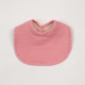 Detail of pink layered cotton crepe baby bib with soft fleece lining and curved design