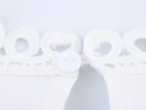 Detailed close-up of white lace collar with a circular button on the elegant blouse