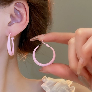 Close-up of pink round hoop earrings on model featuring a smooth polished minimalist finish