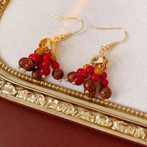 Detailed close-up of Bohemian earrings with red and brown wooden beads in a vintage gold frame