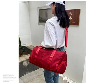 Detail of red nylon travel bag with adjustable strap and side zipper pocket