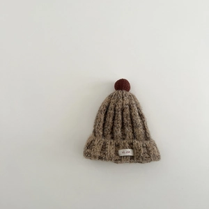 Detail der Strickmütze mit dicker Wolltextur, braunem Bommel und weißem Etikett-Design