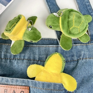 Detailed view of plush green turtle keychains hanging on a blue denim pocket