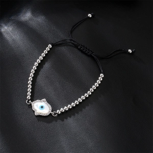 Macro detail of Hamsa Hand and Evil Eye charm on woven beaded adjustable bracelet