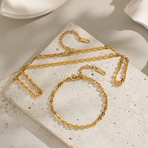 Ensemble collier et bracelet en chaîne d'acier inoxydable doré sur une plaque de pierre
