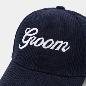 Detail of white Groom embroidery on navy corduroy baseball cap with fine stitching