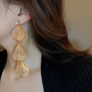 Close-up of golden triple-layered leaf tassel earrings with sparkling white diamonds