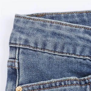 Gros plan sur les coutures fines et la texture denim bleu de la taille mi-haute