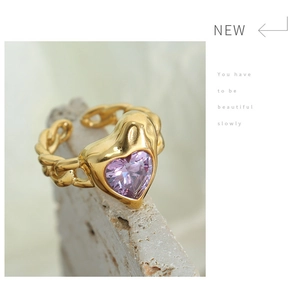 Macro detail of gold plated heart ring featuring purple zircon and cuban chain band