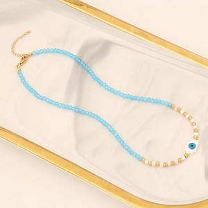 Hand of Fatima evil eye necklace with blue beads on white marble tray background