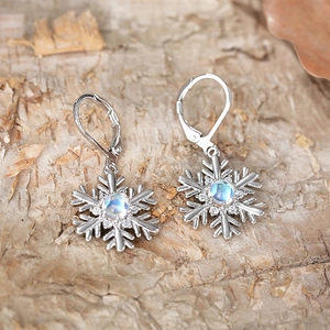 Vue macro de boucles d'oreilles flocon de neige en argent avec pierre de lune sur bois brut