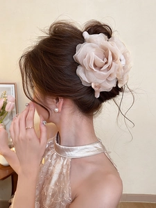 Detail of elegant champagne fabric rose hair claw clip worn on a sophisticated updo