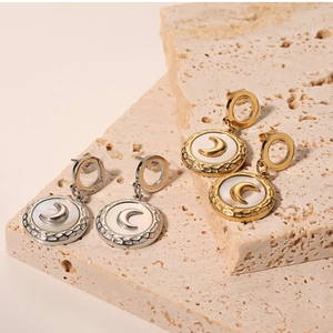 Detail of round shell pendants with moon relief on gold and silver stainless steel earrings