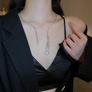 Close-up of elegant gold rhinestone tassel necklace on model in black suit jacket