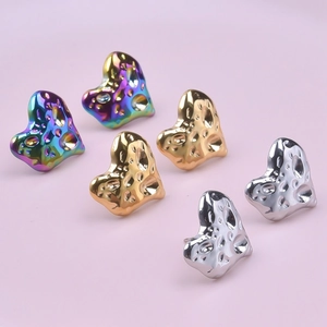Macro detail of heart-shaped earrings with lava texture in rainbow, gold, and silver finishes