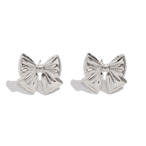 Detailed close-up of silver bow earrings with polished texture and knot design