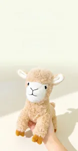 Close-up of a small plush white sheep doll being held in hand with soft warm lighting