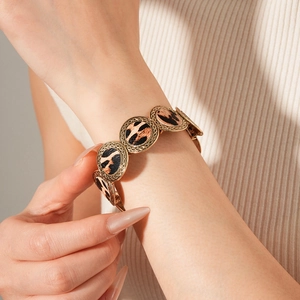 Detailed view of leopard print texture and embossed gold weave on a vintage bracelet