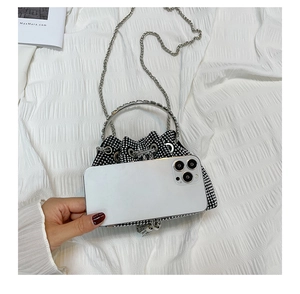 Mini bucket bag with black rhinestones and chain strap compared with phone size