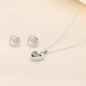 Detailed close-up of silver steel heart jewelry set with LOVE engraving and stud earrings