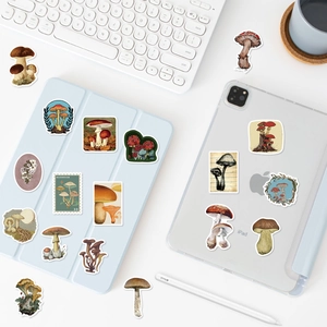 Detail view of vintage mushroom stickers on tablet and keyboard with retro botanical art