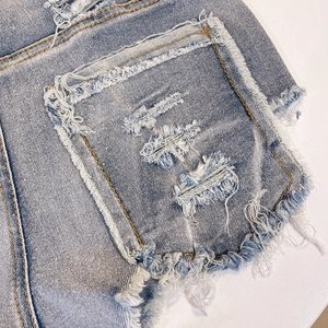 Dettaglio di pantaloncini di denim azzurro con strappi pesanti e bordi sfrangiati