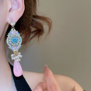 Detail of luxury teardrop flower earrings with sky blue stones and pink resin pendants