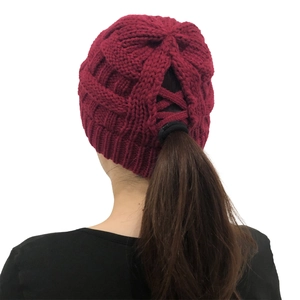 Detail of burgundy ponytail knit hat with cross elastic back opening for messy buns