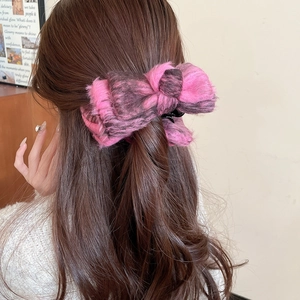 Close-up of elegant pink and black velvet bow hair clip worn on long wavy hair