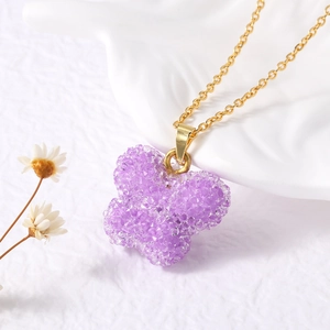 Détail d'un pendentif papillon violet avec texture de cristal sur une chaîne dorée