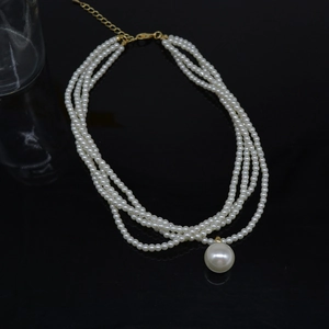 Detail view of multi-layer pearl necklace with four strands and a large center drop pendant