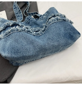 Gros plan d'un sac cabas en jean bleu avec des détails effilochés élégants aux bords