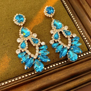 Macro detail of drop-shaped blue crystal earrings with gold plating and tassel fringe