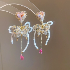 Detailed macro shot of butterfly heart pearl drop earrings with champagne gold finish