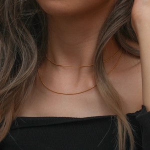 Close-up of minimalist double-layer gold snake bone chain necklace on model neck
