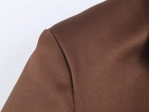 Détail macro de la couture d'épaule du blazer en satin marron et texture fine