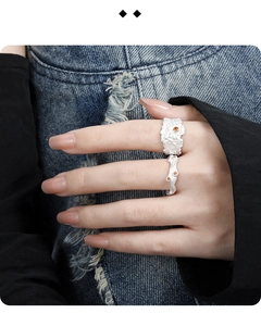 Detailed shot of irregular texture silver rings with orange zircon on denim background