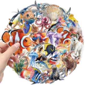 Macro view of clear PET ocean creature stickers showing a hand holding a clownfish decal