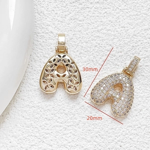 Macro view of gold-plated letter A pendant with cubic zirconia and floral hollow back