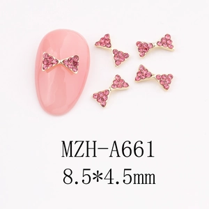 Macro view of 8.5x4.5mm gold metal bow nail charms with pink rhinestones