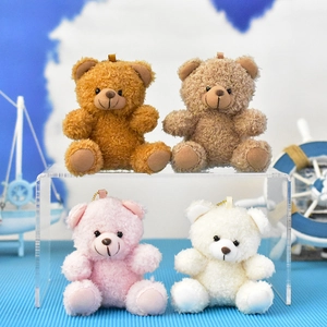 Detail view of four colorful mini teddy bear plush keychains on a clear display stand