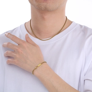 Dettaglio di un set collana e bracciale in acciaio al titanio dorato con maglia a spiga
