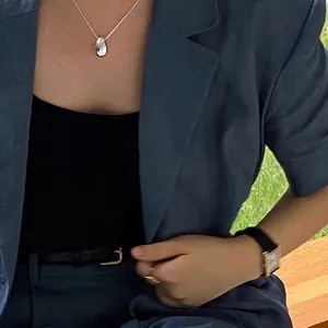 Minimalist silver water drop pendant necklace with a polished mirror finish on model