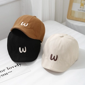 Minimalist cotton baby caps with embroidered W letter in brown, black and beige colors