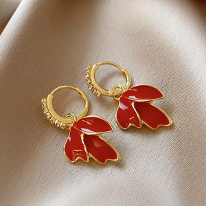 Elegant festive red leaf earrings with gold clasp and zircon stones on silk fabric